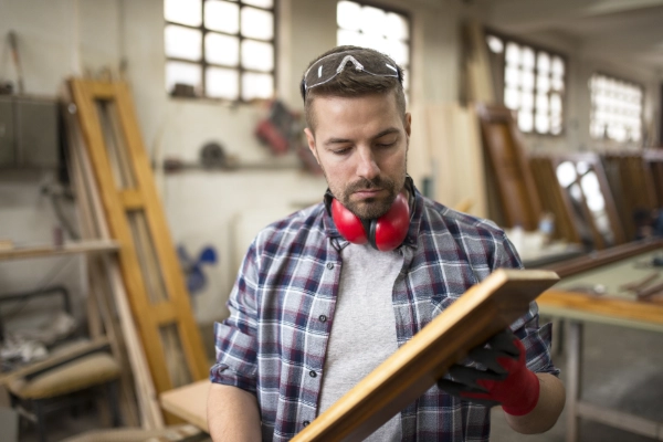 Profesional carpintero seleccionando tableros de madera en almacén especializado de Madrid